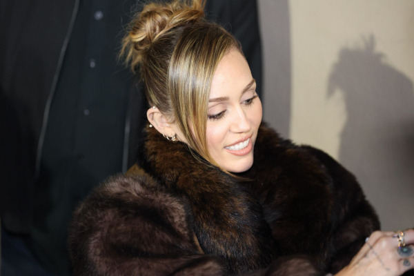 Miley Cyrus signs autographs in an updo and fur coat.
